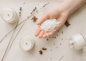 Flat lay of natural candle making with granulated wax, star anise, and lavender on a beige background.